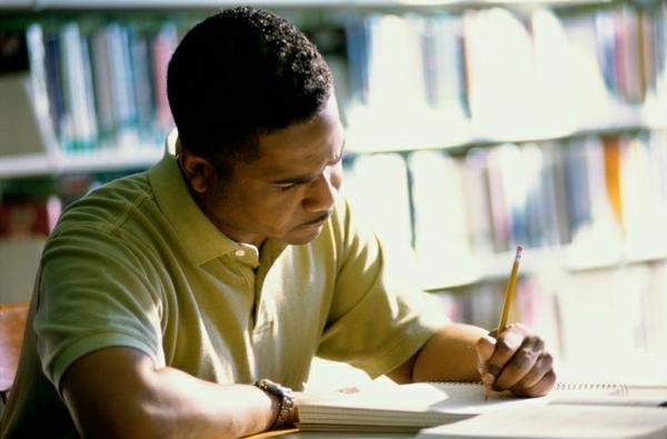 Man sitting at a desk writing his resume.